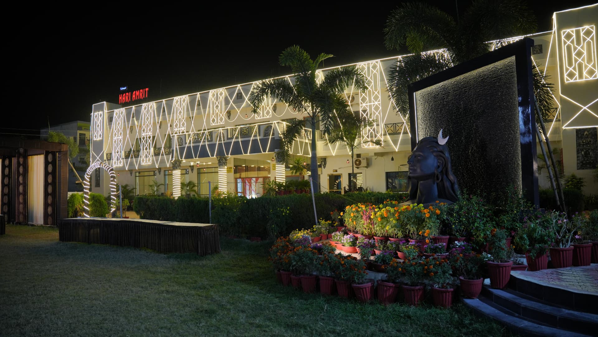 Hari Amrit resort building lit with white light patterns at night, beside the garden