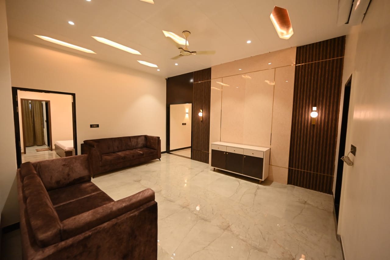 Sitting area at Abhinandan Palace with sofas, wood-panelled wall and marble floor, opening onto a bedroom