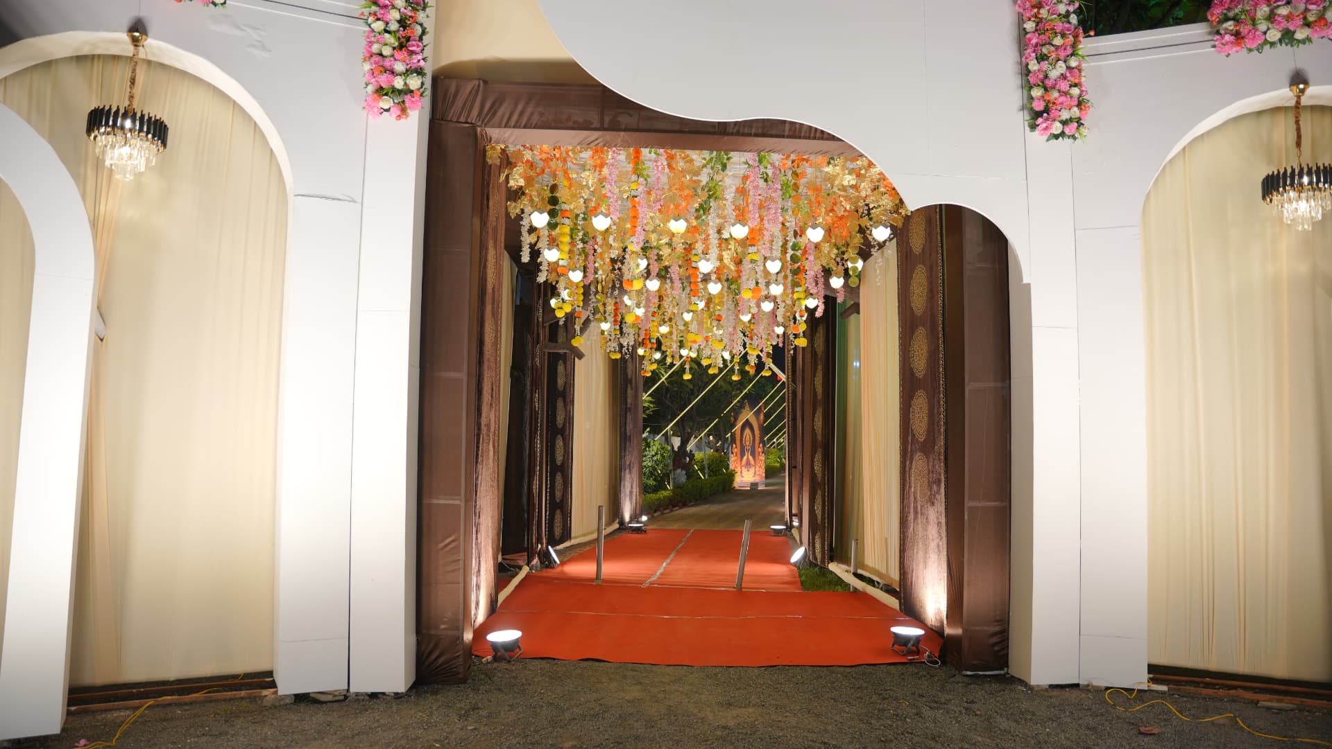 Decorated entrance passage at Hari Amrit with hanging flowers, chandeliers and a red carpet