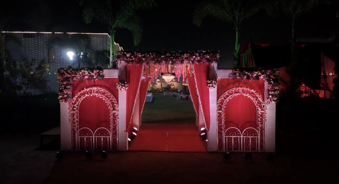 Abhinandan Palace welcome gate decorated with red drapes, floral garlands and a red carpet leading to the lawn